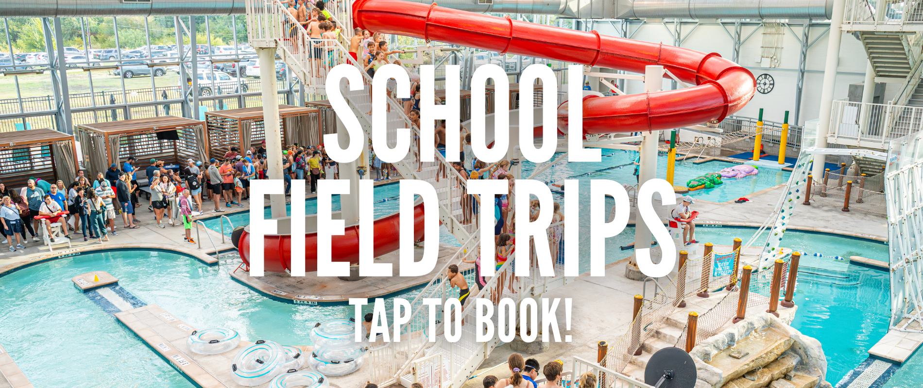 Indoor water park with a red slide and pools, filled with visitors and surrounding seating areas. Large text overlay reads "School Field Trips Tap to Book!"
